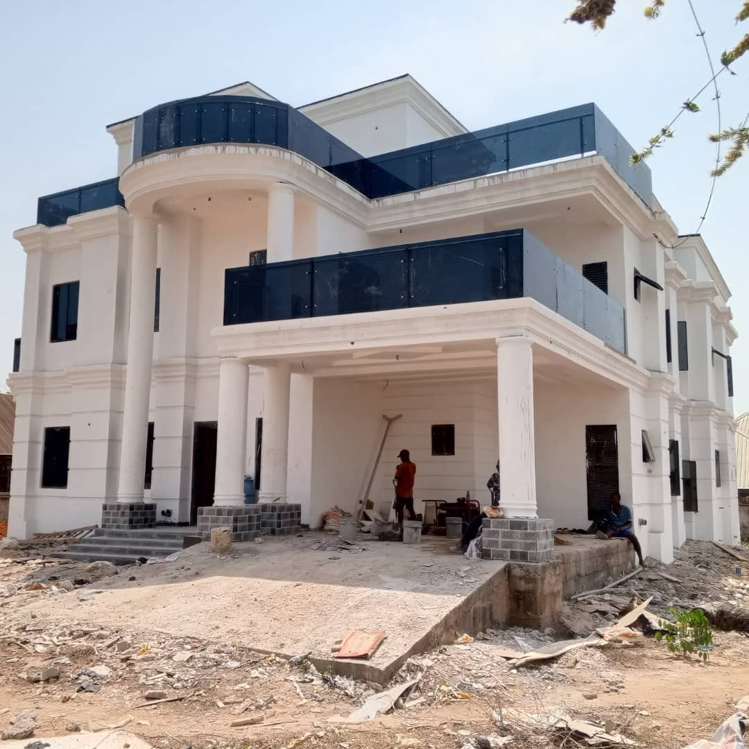 A completed white three-storey residence with dark glass balconies built by Ezhiomo