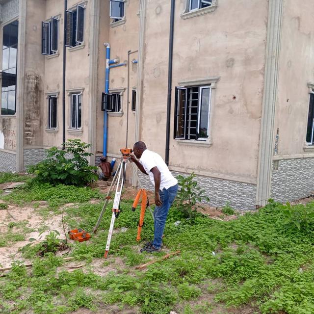 Ezhiomo surveyor setting out levels with an automatic level beside a finished building